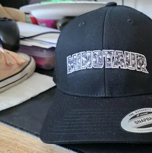 Black snapback trucker with a large arched white Minotaur wordmark