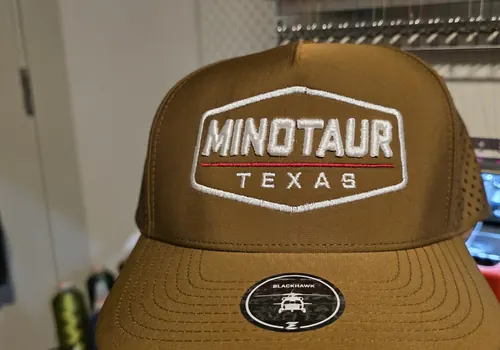 Tan cap with an embroidered white Minotaur Texas hexagon badge